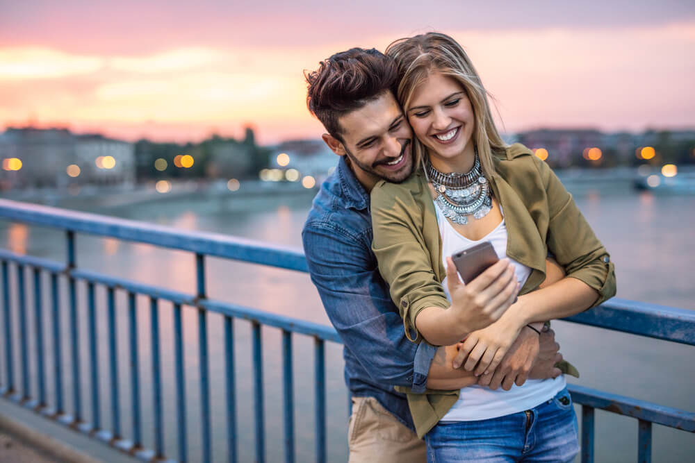 happy couple looking at phone happy couple looking at phone